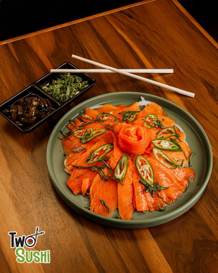 Sashimi de salmón con chiles serranos sobre plato verde